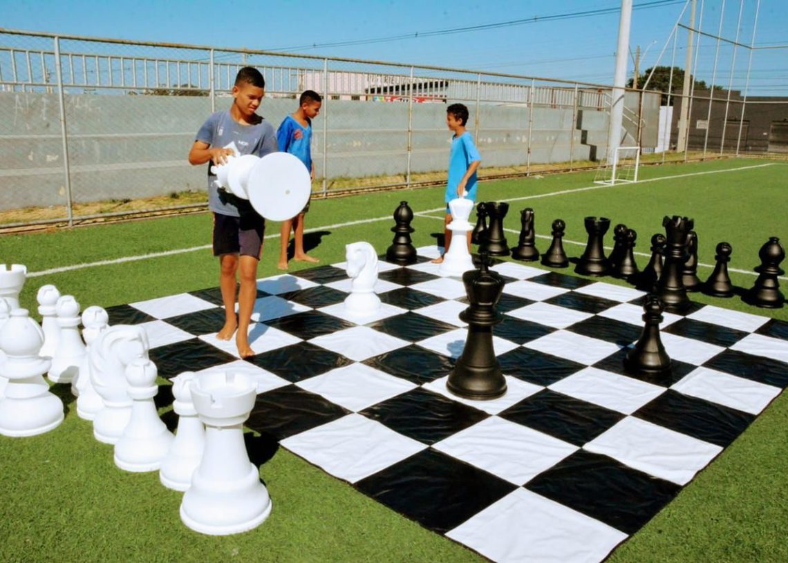 crianças jogando xadrez gigante