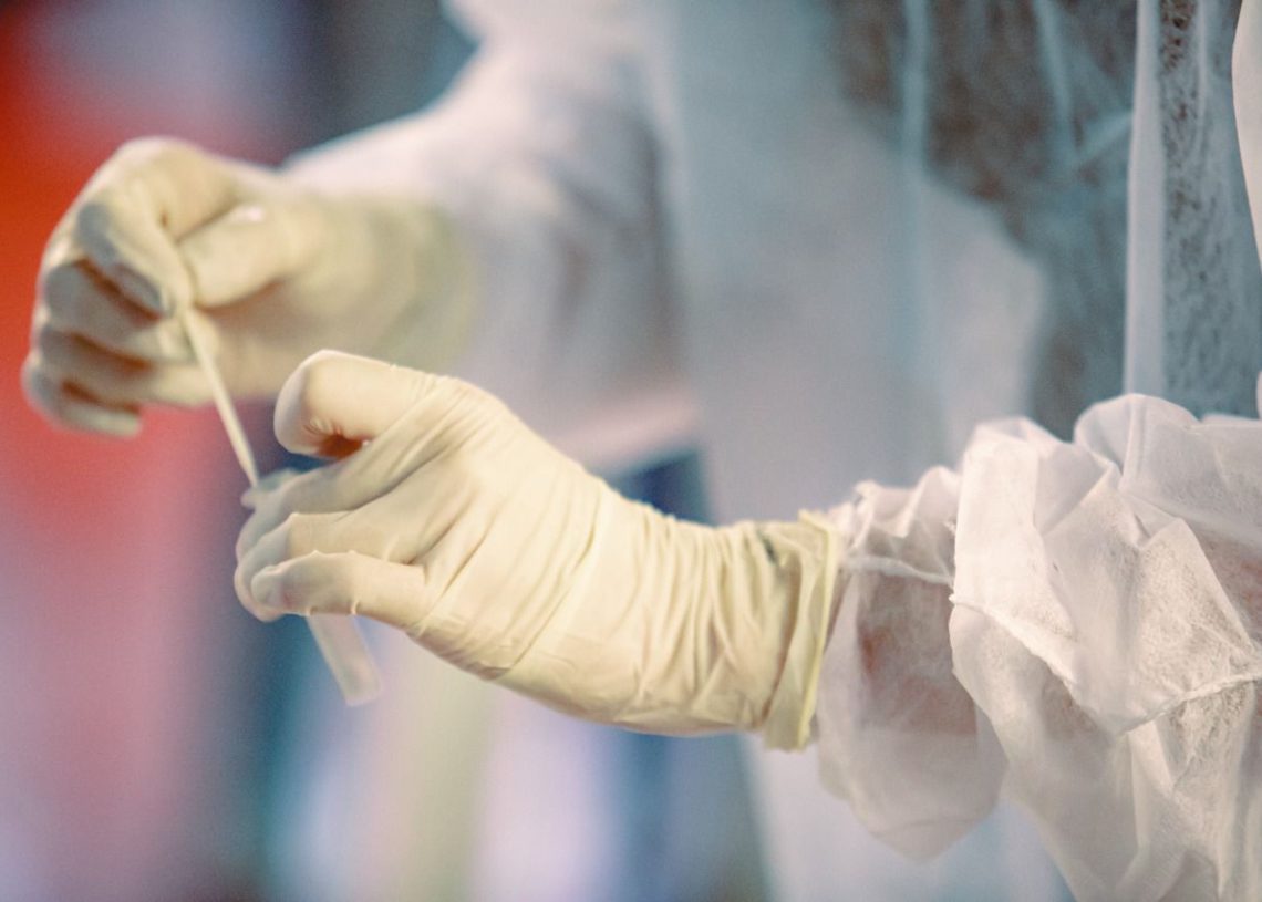 pessoa, de luvas, manuseando teste de covid