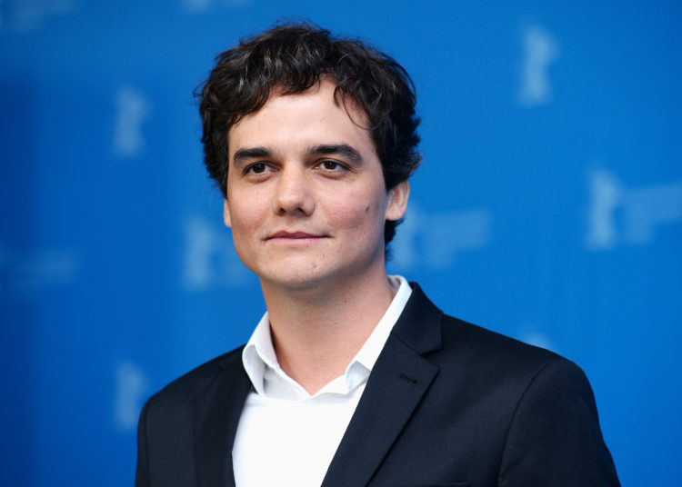 ator wagner moura sorrindo, com fundo azul