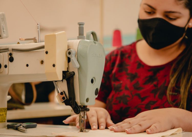 moça utilizando equipamento de costura e confecção