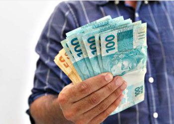 #pratodomundover imagem mostra uma pessoa com várias notas de dinheiro na mão