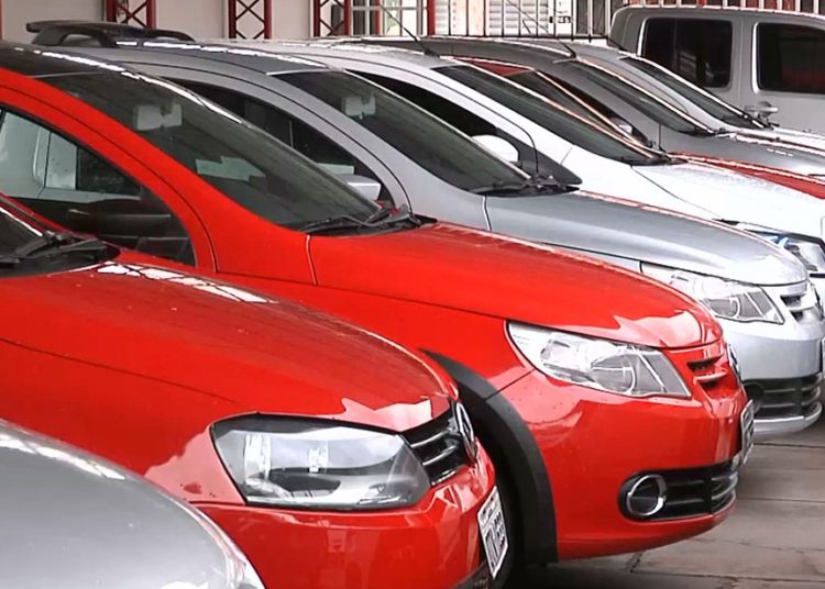 veículos usados em fila, alguns vermelhos e outros na cor prata