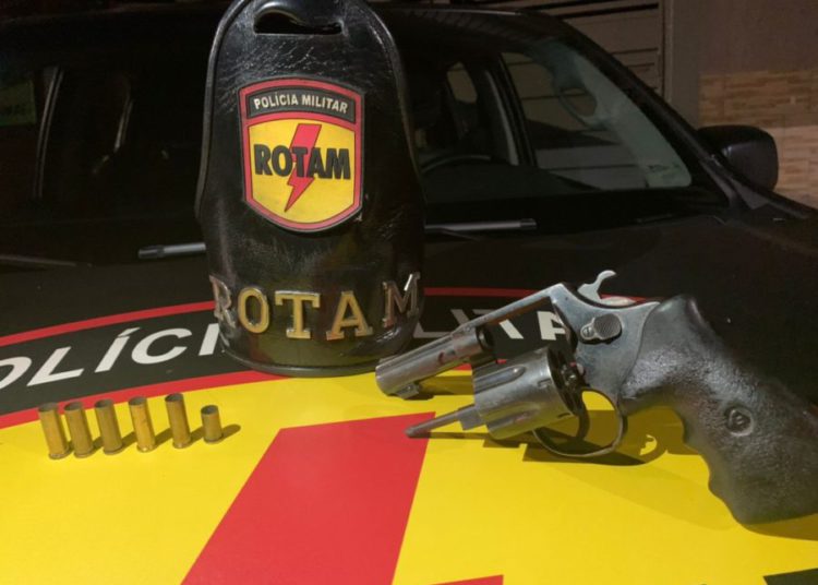 imagem com símbolo da rotam e arma descarregada apoiadas em capô de viatura