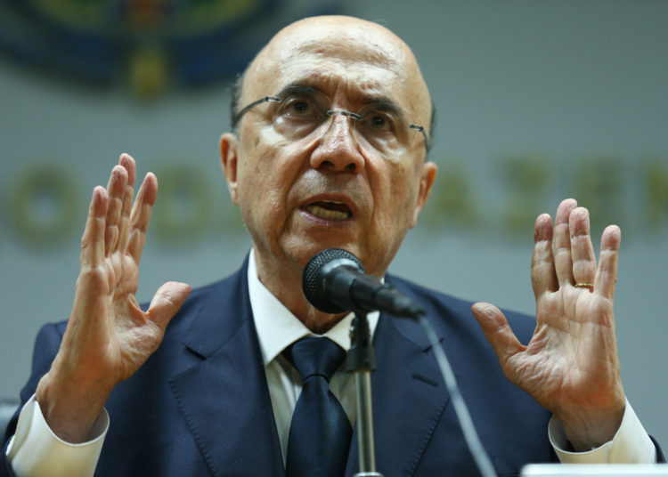 foto de henrique meirelles, discursando em microfone e gesticulando com as mãos