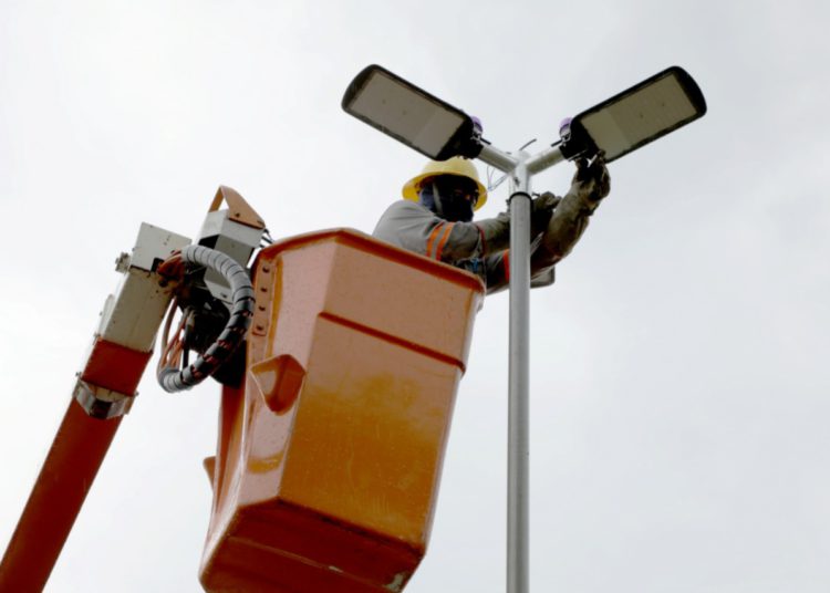 foto de homem realizando a instalação de lâmpada de Led em poste