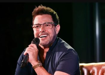 foto do cantor zezé di camargo durante show, com microfone em mãos e sorrindo