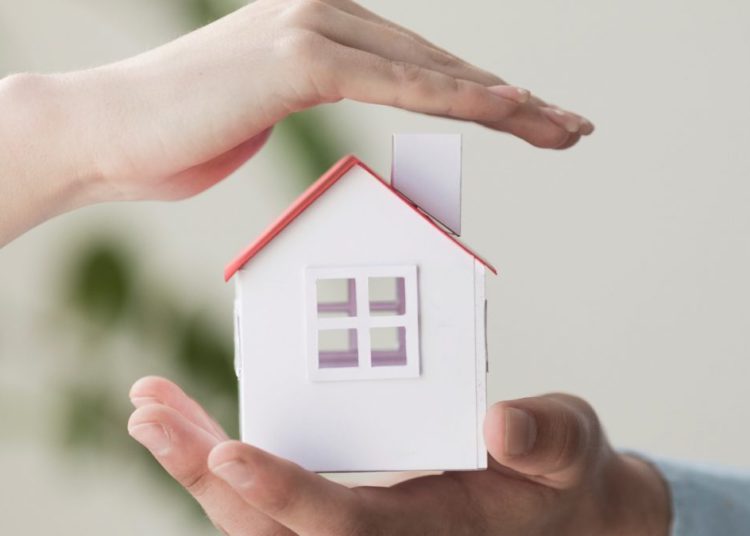 foto de pessoa segurando casa em miniatura, representando o bem de família