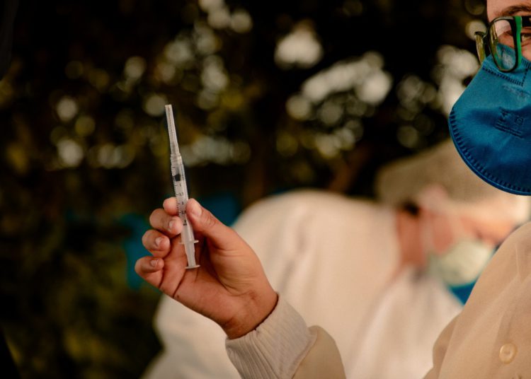 foto de pessoa segurando vacina contra a covid, em seringa