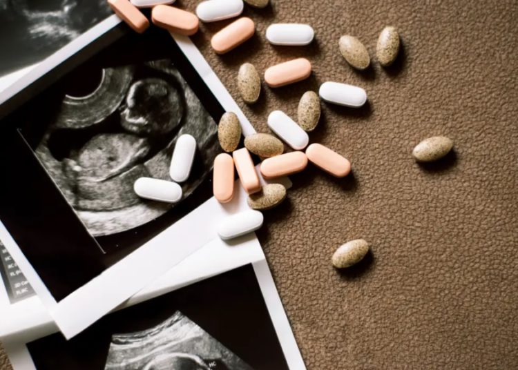 foto de ultrassonografia de bebê e pílulas ao lado, representando o aborto