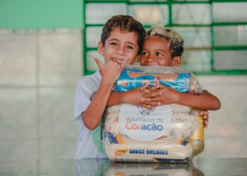 foto de crianças abraçadas junto a cesta básica de alimentos, fruto da ação de assistência social