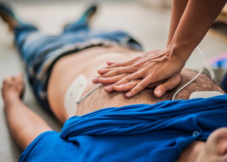 foto de atuação do suporte básico de vida, com pessoa com as mãos entrelaçadas no peito de outra pessoa