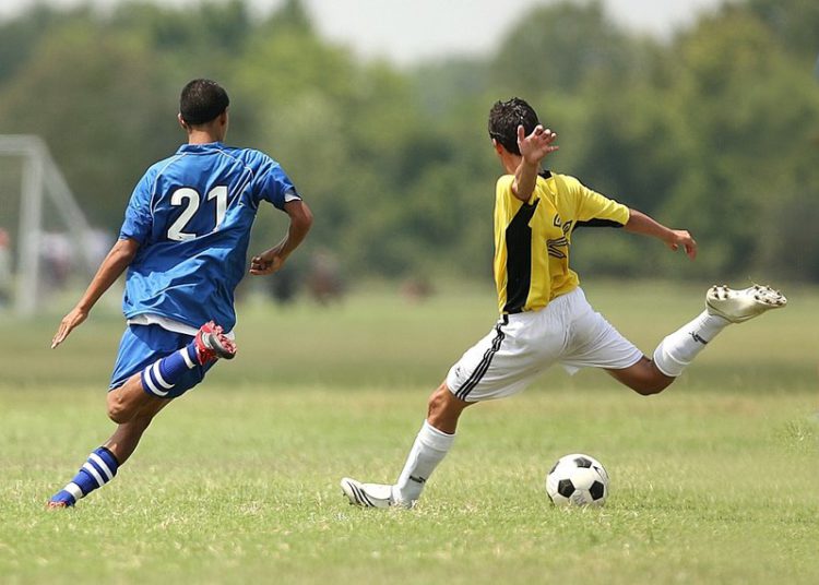 foto de disputa de campeonato amador ,com dois atletas disputando bola no gramado