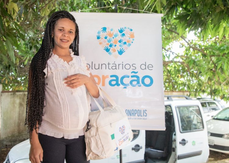 foto de gestante fazendo pose em frente a cartaz do voluntários de coração