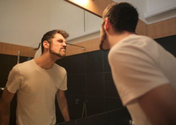 foto de homem em frente ao espelho, fazendo careta