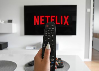 foto de controle de televisão e, ao fundo, logo da netflix