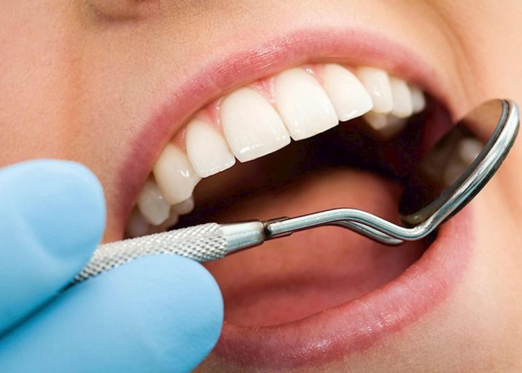 foto de dentista mexendo em dente de paciente, destacando a odontologia