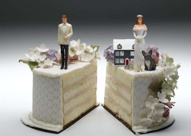 foto de bolo cortado ao meio, com uma metade tendo um boneco de noivo e outra de noiva, em referência ao regime de bens do casamento