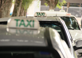 foto de três táxis enfileirados, com taxistas dentro