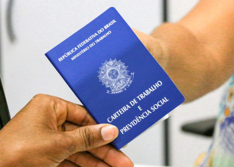 foto de carteira de trabalho sendo passada de uma mão para outra