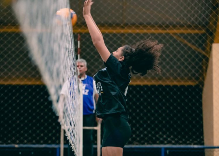 foto de atleta do vôlei em atuação, bloqueando ponto na rede
