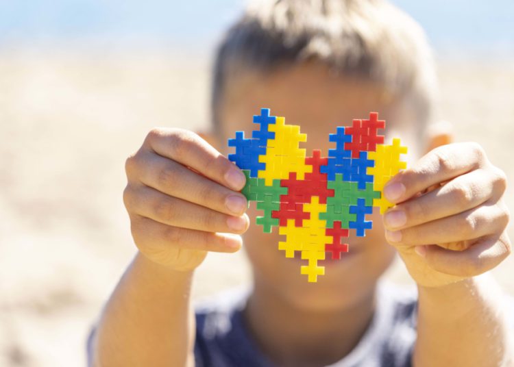 foto de criança com coração de quebra cabeça colorido, representando o autismo