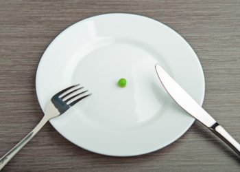 foto de prato branco com apenas uma ervilha em seu centro, representando a fome