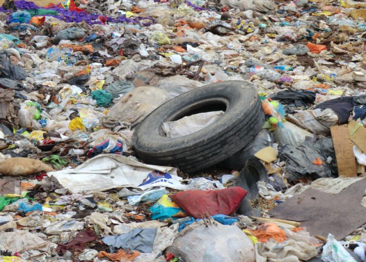 foto de uma imensidão de lixo urbano, com pneu velho em foco