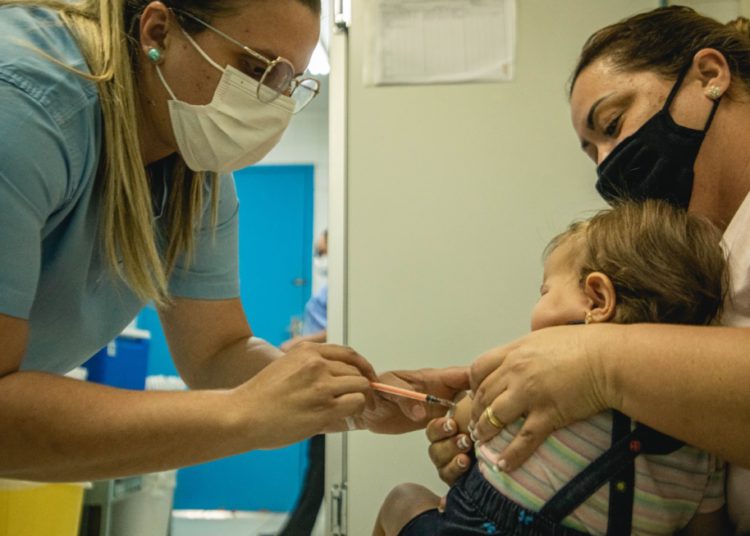 foto de moça aplicando vacina em criança