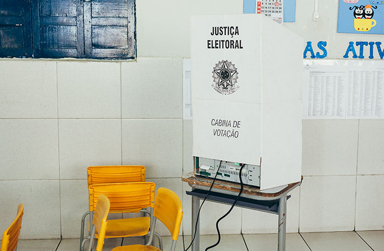 fotode cabine eleitoral, com uma cadeira amarela ao lado