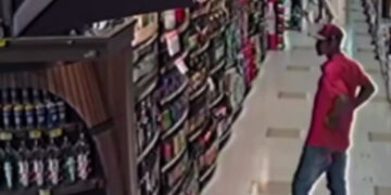 Homem furtando bebida em supermercado