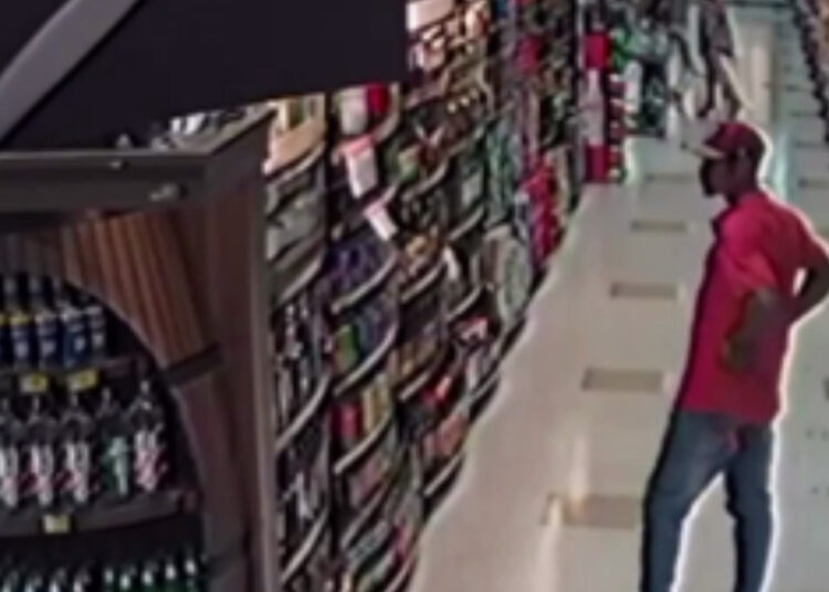 Homem furtando bebida em supermercado