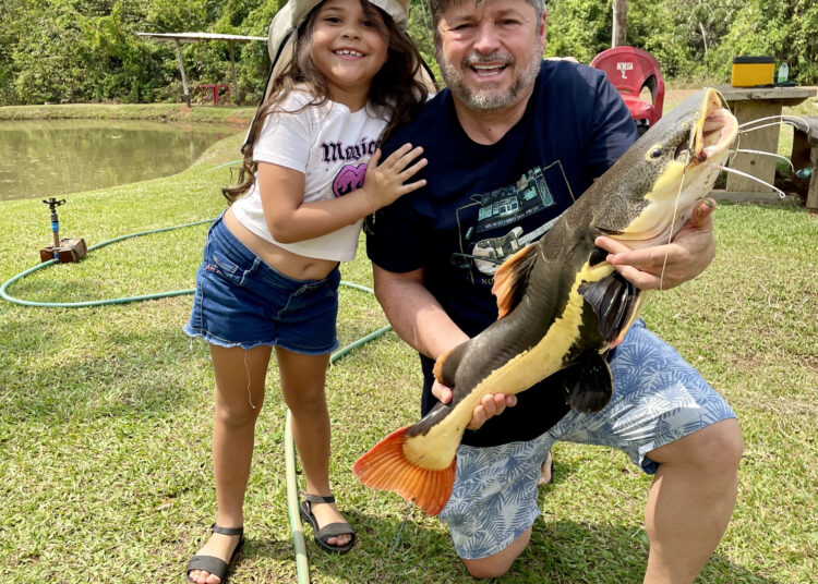 Pequena pescadora Antônia ao lado do avô e da pirarara